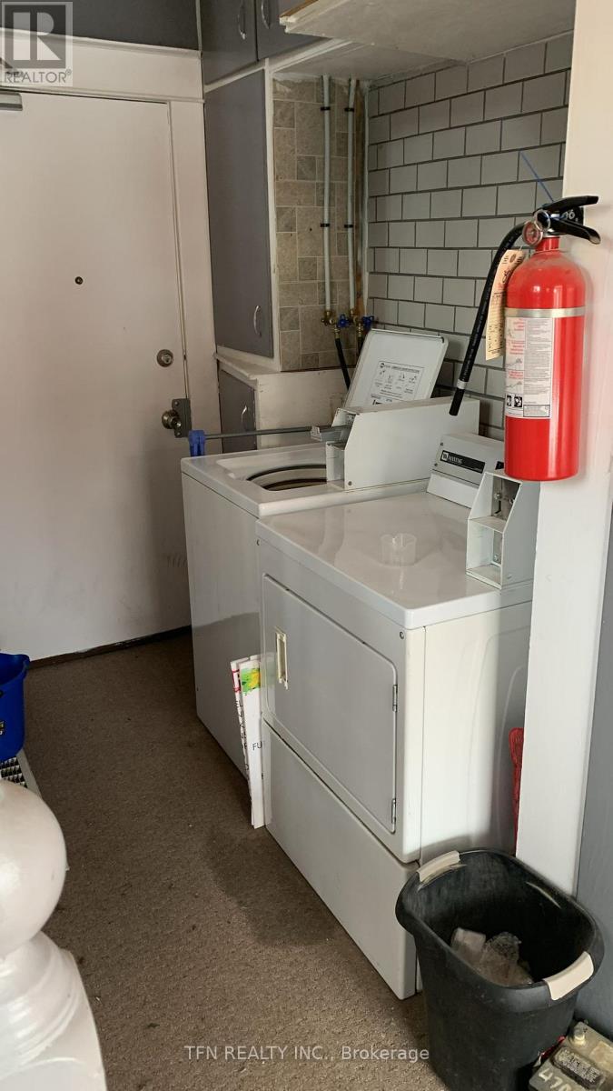A small white kitchen with a red fire extinguisher on the wall.