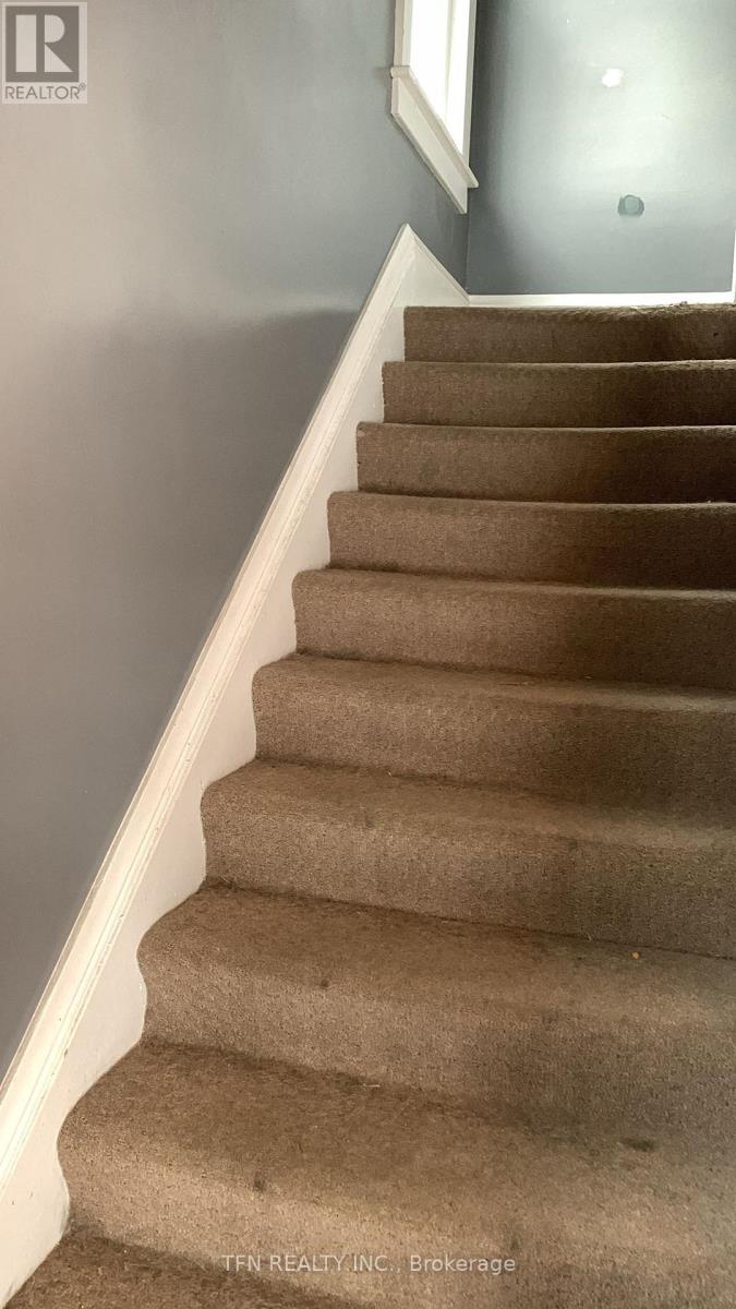 A staircase with beige carpeted steps and white handrails.