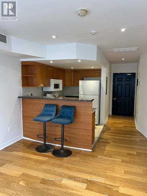A kitchen with a bar stool and a fridge.