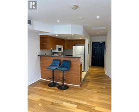 A kitchen with a bar stool and a fridge.
