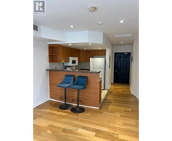 A kitchen with a bar stool and a fridge.