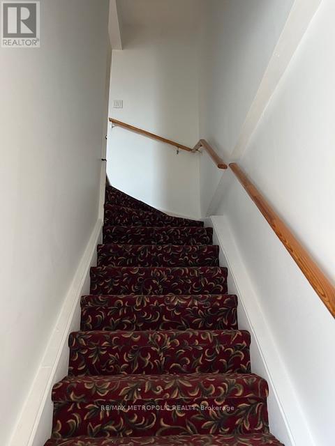 A staircase with a red carpet and wooden handrails.
