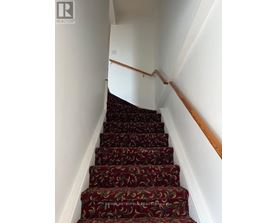 A staircase with a red carpet and wooden handrails.