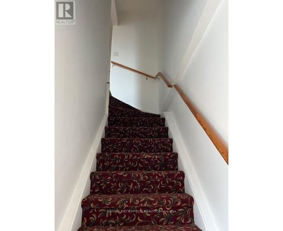 A staircase with a red carpet and wooden handrails.