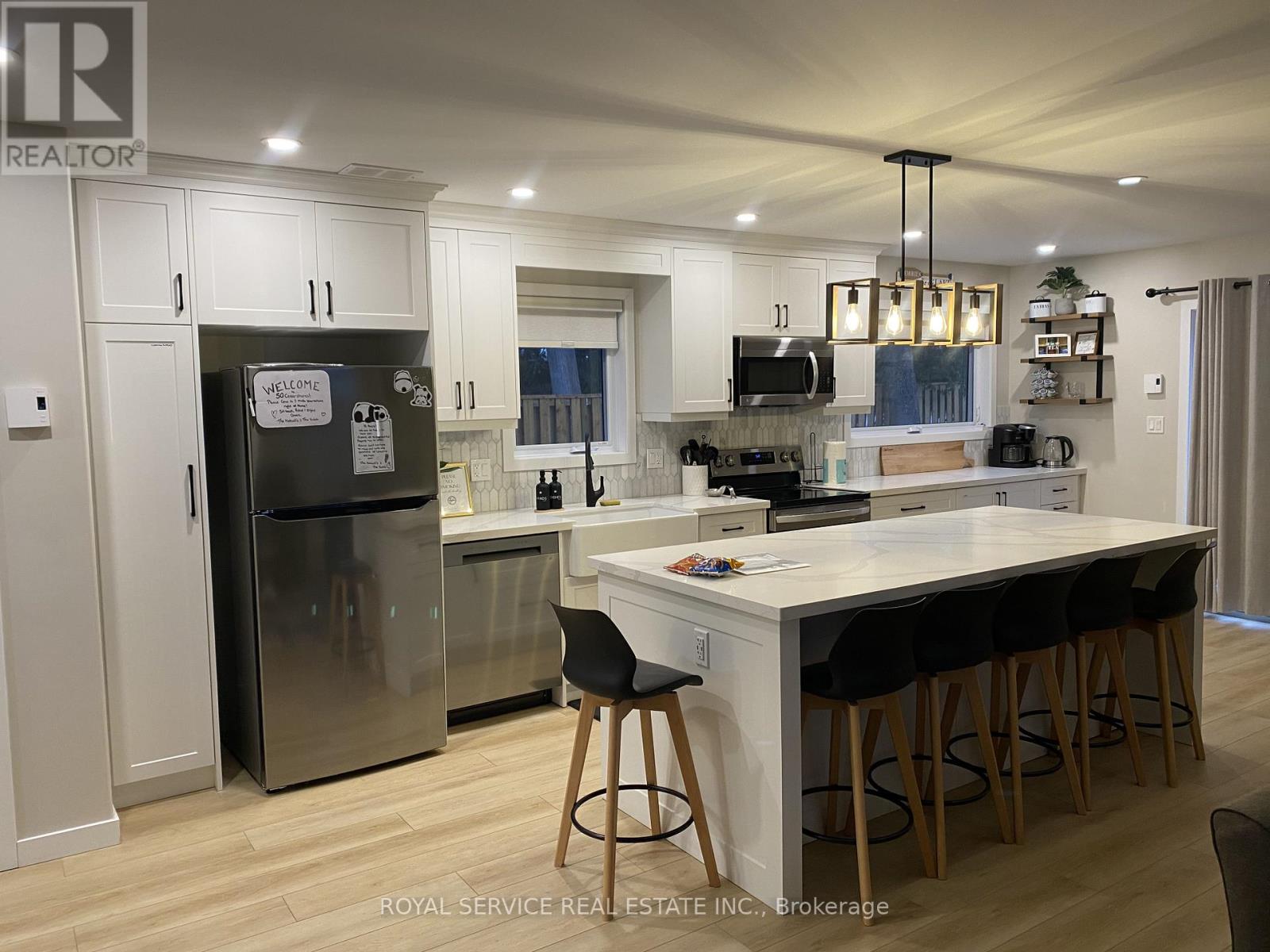 A kitchen with a white island and black bar stools.
