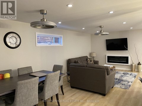 A living room with a grey couch, a dining table with grey chairs, a television, and a fireplace.