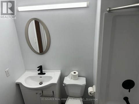 A bathroom with a sink, toilet and mirror.