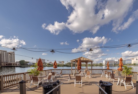 A patio with chairs and umbrellas overlooking a body of water.
