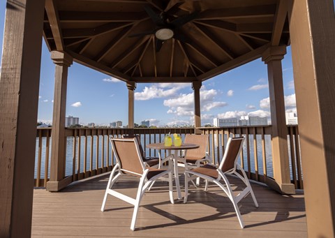 A wooden patio with a table and chairs overlooking a body of water.