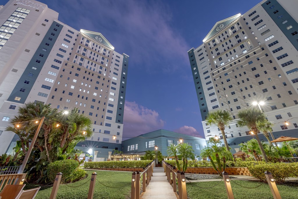 A beautifully lit walkway between two high-rise buildings at dusk.