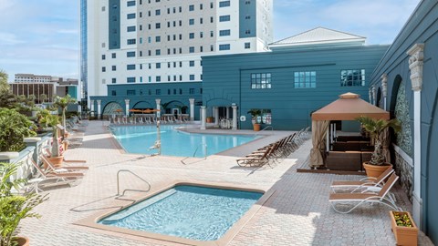 A large swimming pool surrounded by lounge chairs and umbrellas.