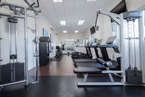 A gym with a variety of equipment including treadmills, weights, and exercise machines.