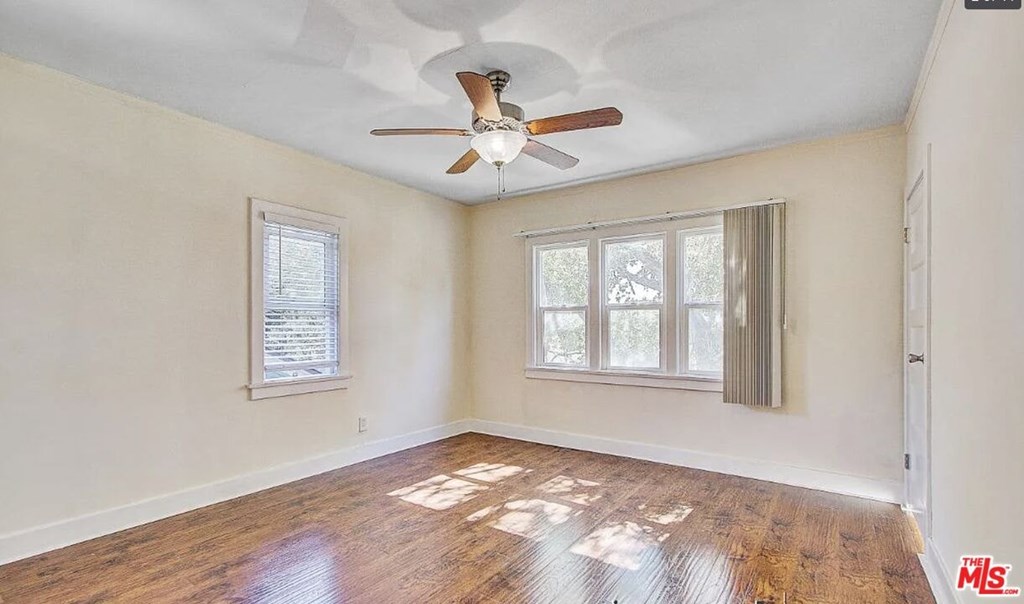 A room with a ceiling fan and a window with blinds.