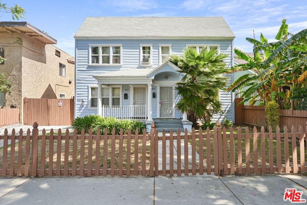 A blue house with a brown fence in front of it.
