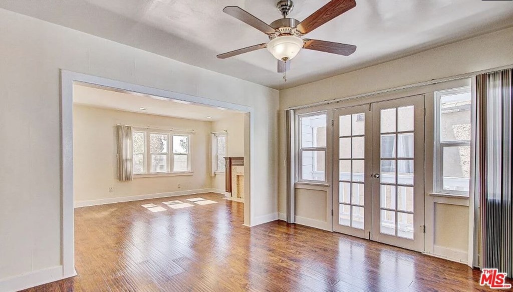 A spacious room with a ceiling fan and hardwood floors.