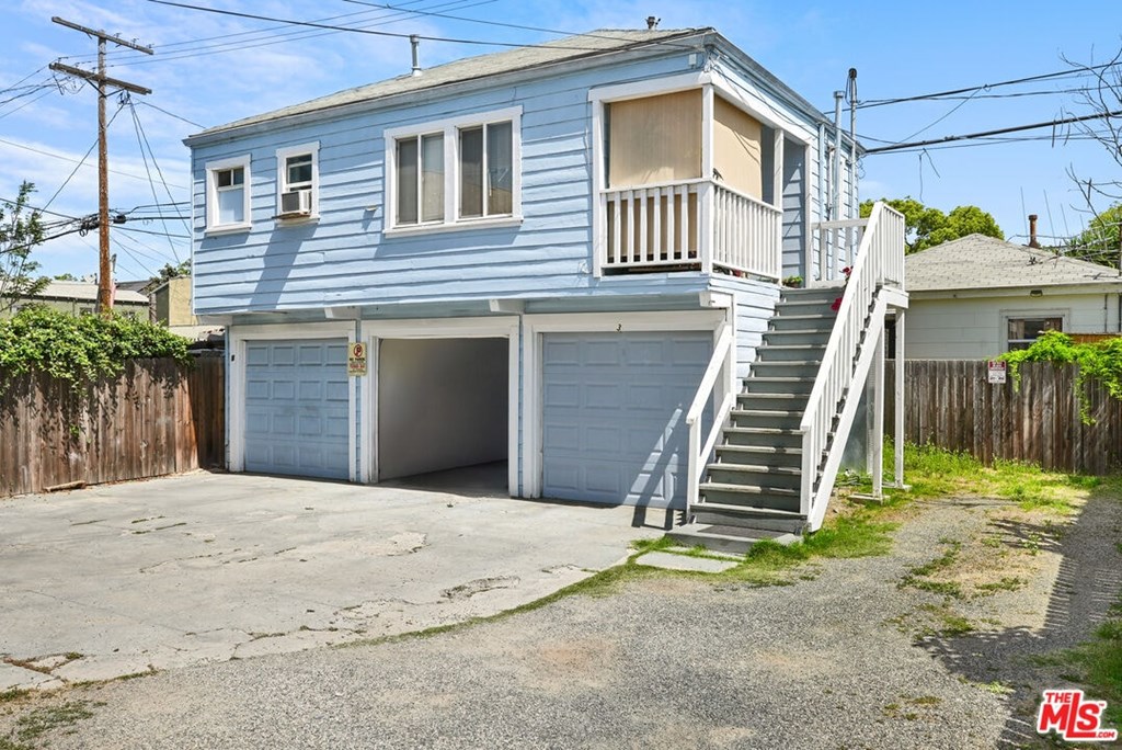 A blue house with a garage and stairs leading to the second floor.