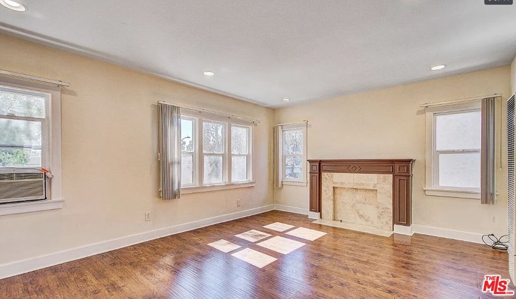 A large empty room with a fireplace and wooden floors.