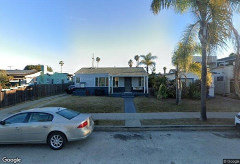 A car is parked in front of a house with a blue door.