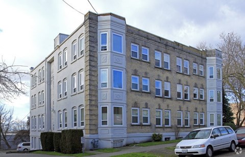 A grey building with blue trimmed windows and a white car parked in front.