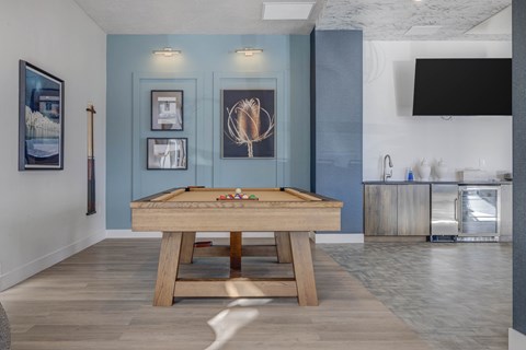 A pool table is in the middle of a room with a blue wall.