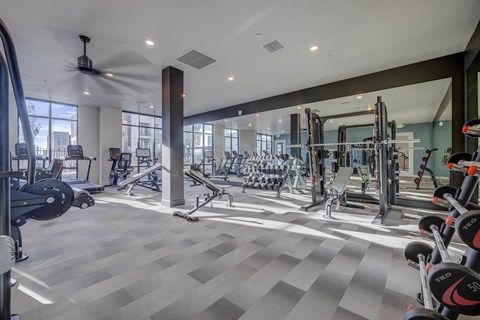 A spacious gym with a variety of equipment and a ceiling fan.