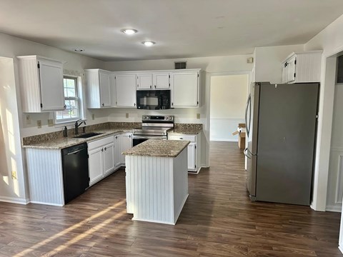 A kitchen with white cabinets and a granite countertop.