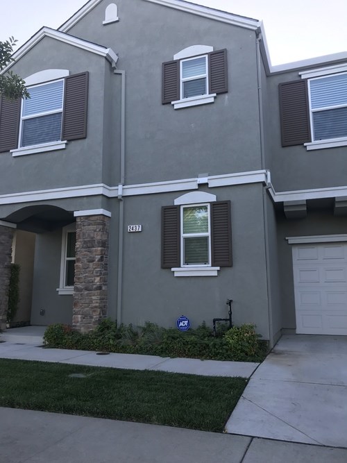 A grey house with a white garage door and a small garden in front.