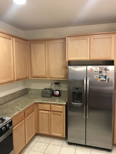 A kitchen with wooden cabinets and a stainless steel refrigerator.