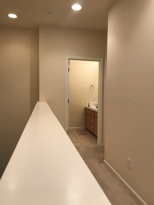 A long white hallway with a door at the end.