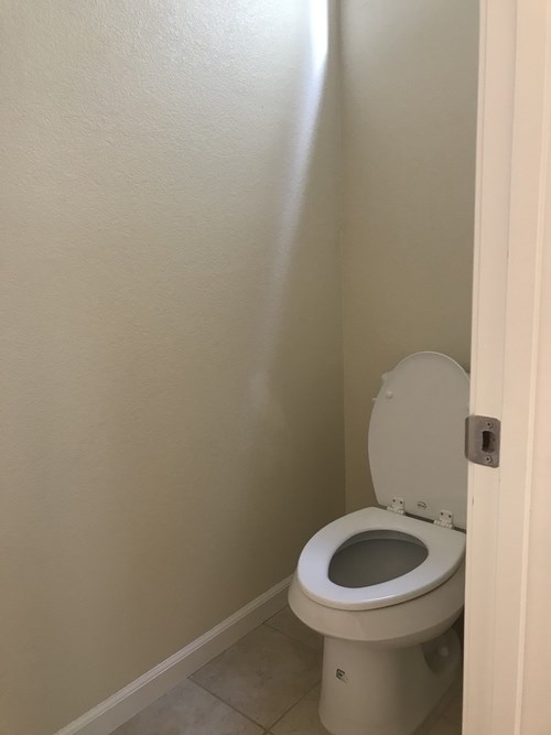 A toilet with the seat up in a small bathroom.