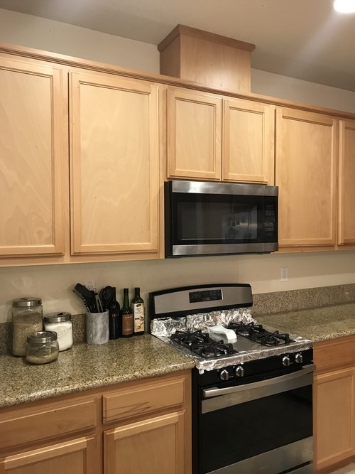 A kitchen with wooden cabinets and a black stove top.