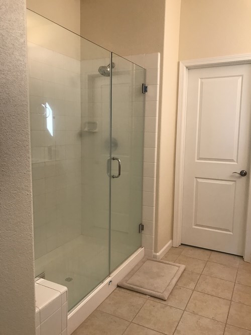 A white door is next to a glass shower stall.