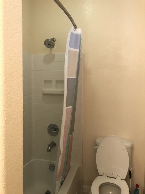 A white toilet is in a bathroom with a glass shower stall.