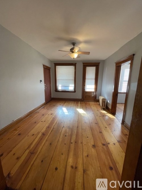 A room with wooden flooring and a ceiling fan.