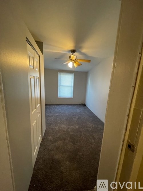 A room with a ceiling fan and carpeted floor.