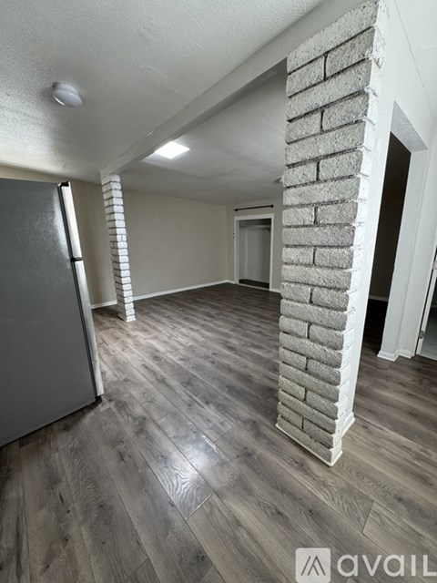 A room with a brick pillar and wooden flooring.