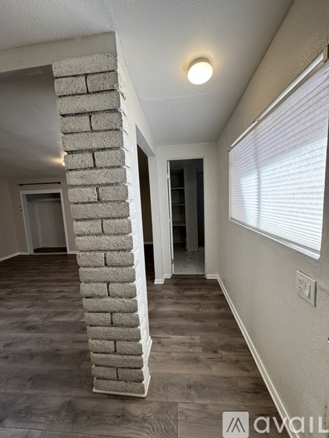 A room with a white column and wooden flooring.