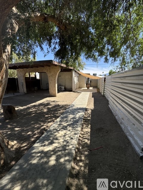 A patio area with a tree and a building in the background.