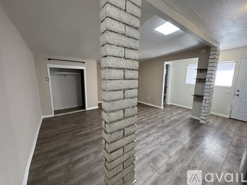 A room with a column made of concrete blocks and wooden flooring.