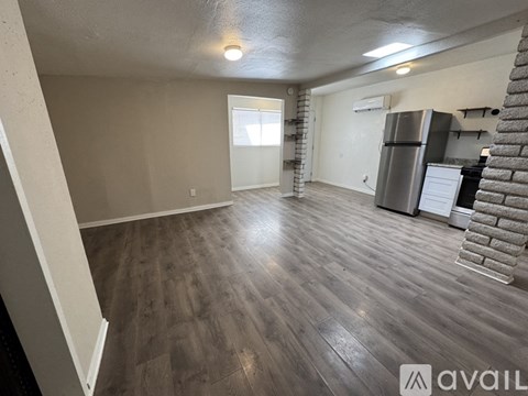 A spacious room with wooden flooring and a brick column.