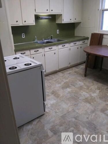A kitchen with a white stove and white cabinets.