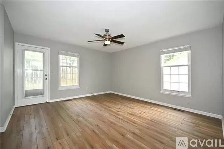 A room with a ceiling fan and two windows.