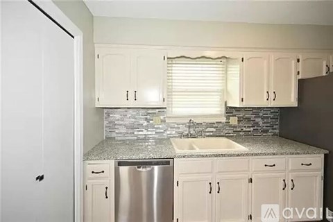 A kitchen with white cabinets and a granite countertop.