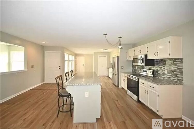 A kitchen with a bar stool in front of a white fridge.
