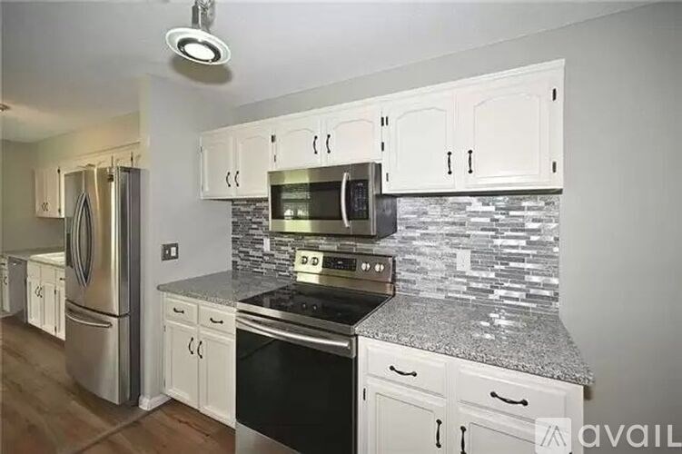 A kitchen with white cabinets and a granite countertop.