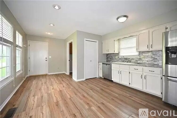 A kitchen with white cabinets and a wooden floor.