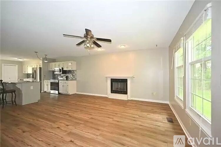 A living room with a fireplace and a kitchen in the background.