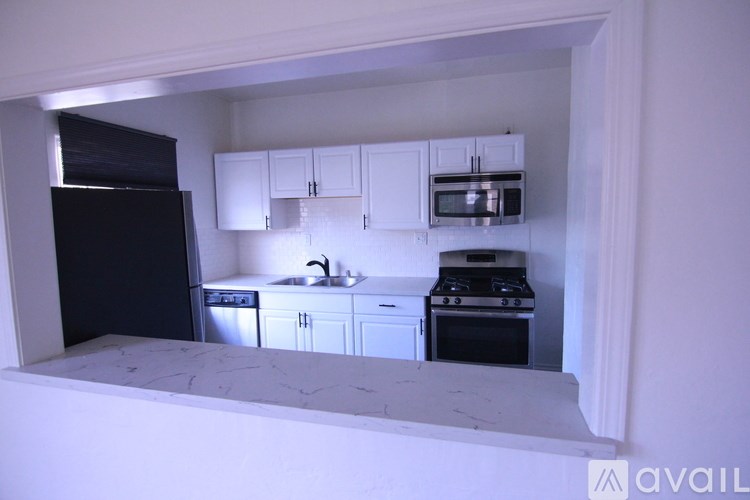 A kitchen with white cabinets and black appliances.