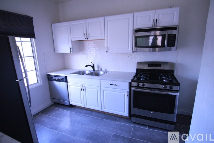 A kitchen with white cabinets and black appliances.