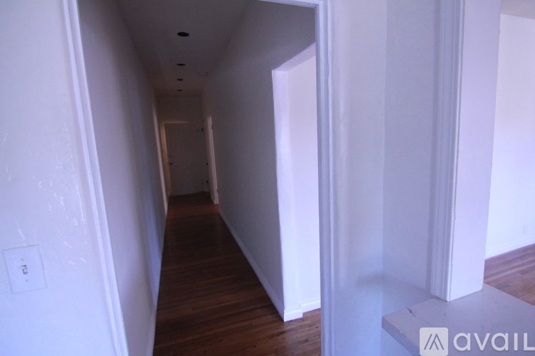 A long hallway with white walls and wood floors.